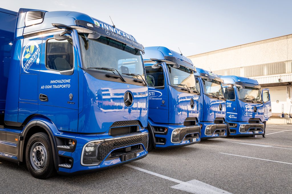 Fila di furgoni elettrici Mercedes-Benz blu parcheggiati uno accanto all'altro, con la scritta “100% Elettrico”