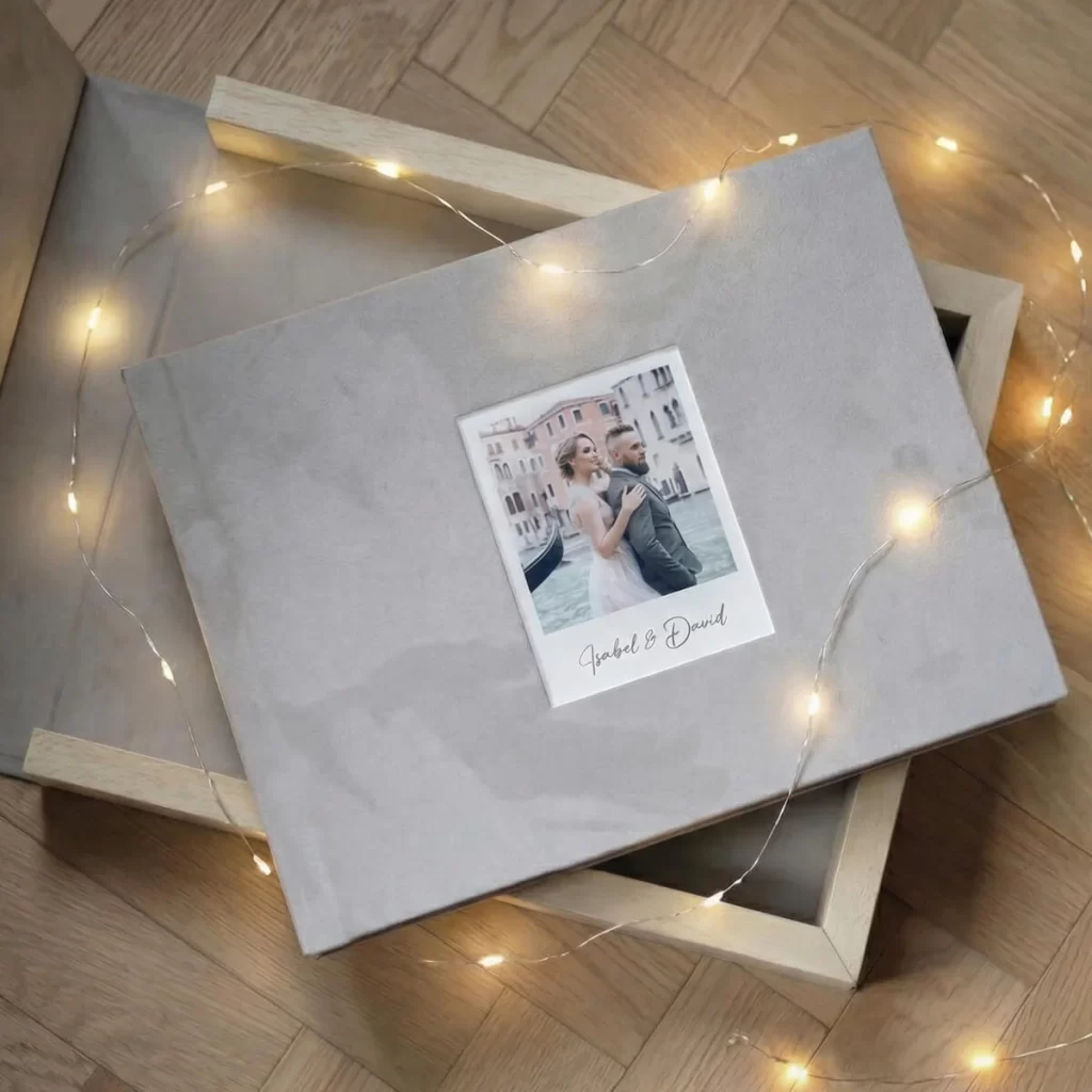 Un elegante album fotografico con la foto di una coppia in copertina, circondato da lucine luminose che creano un'atmosfera romantica