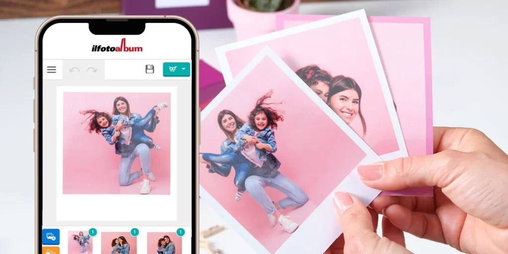 Una mano impugna alcune foto stampate che ritraggono due donne sorridenti in un momento giocoso su uno sfondo rosa. Accanto, uno smartphone mostra la stessa immagine su un'app fotografica.